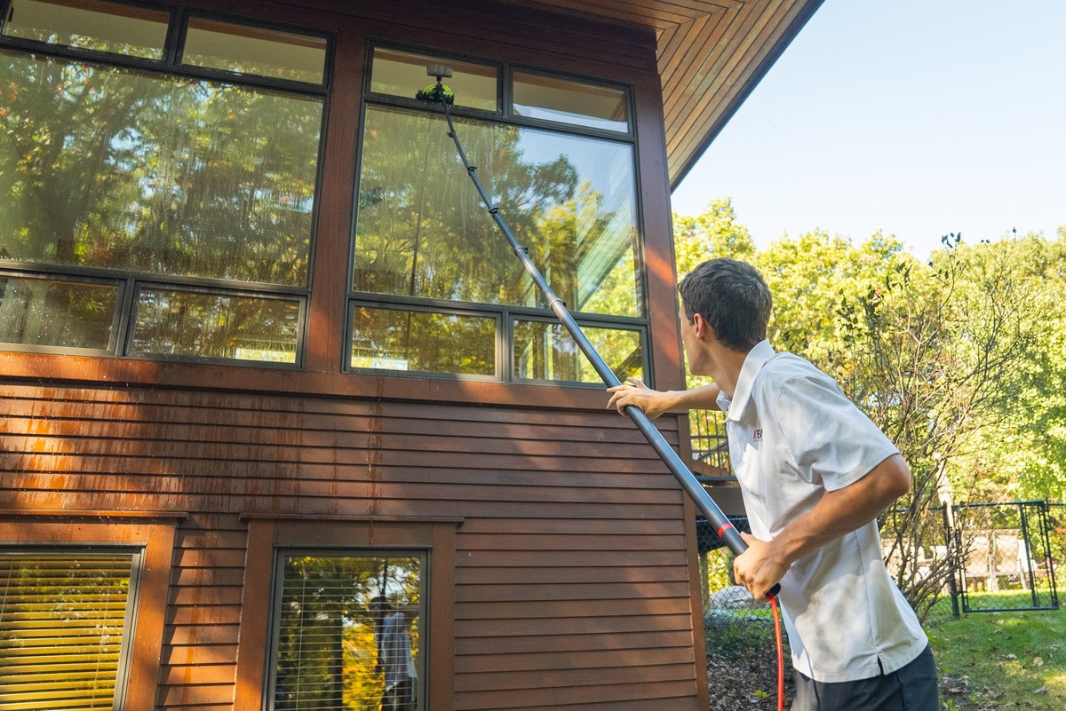 Cleaning tall second-story windows with a water-fed pole and brush