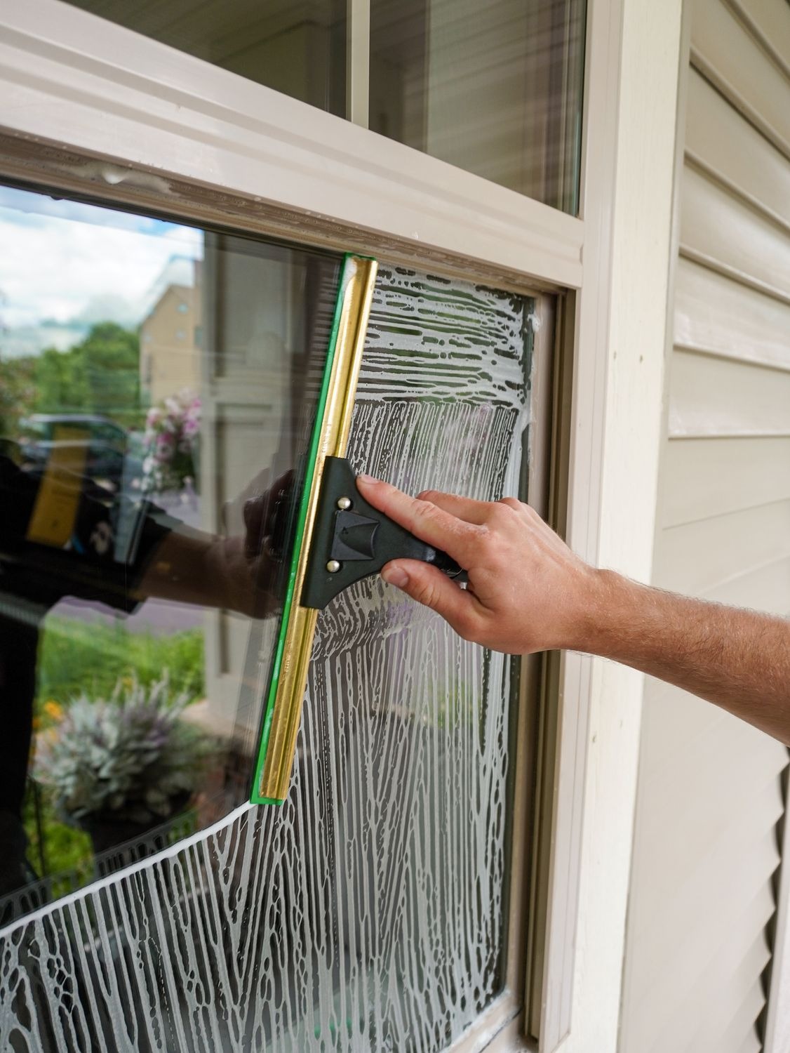 Technician cleaning interior window glass with a squeegee