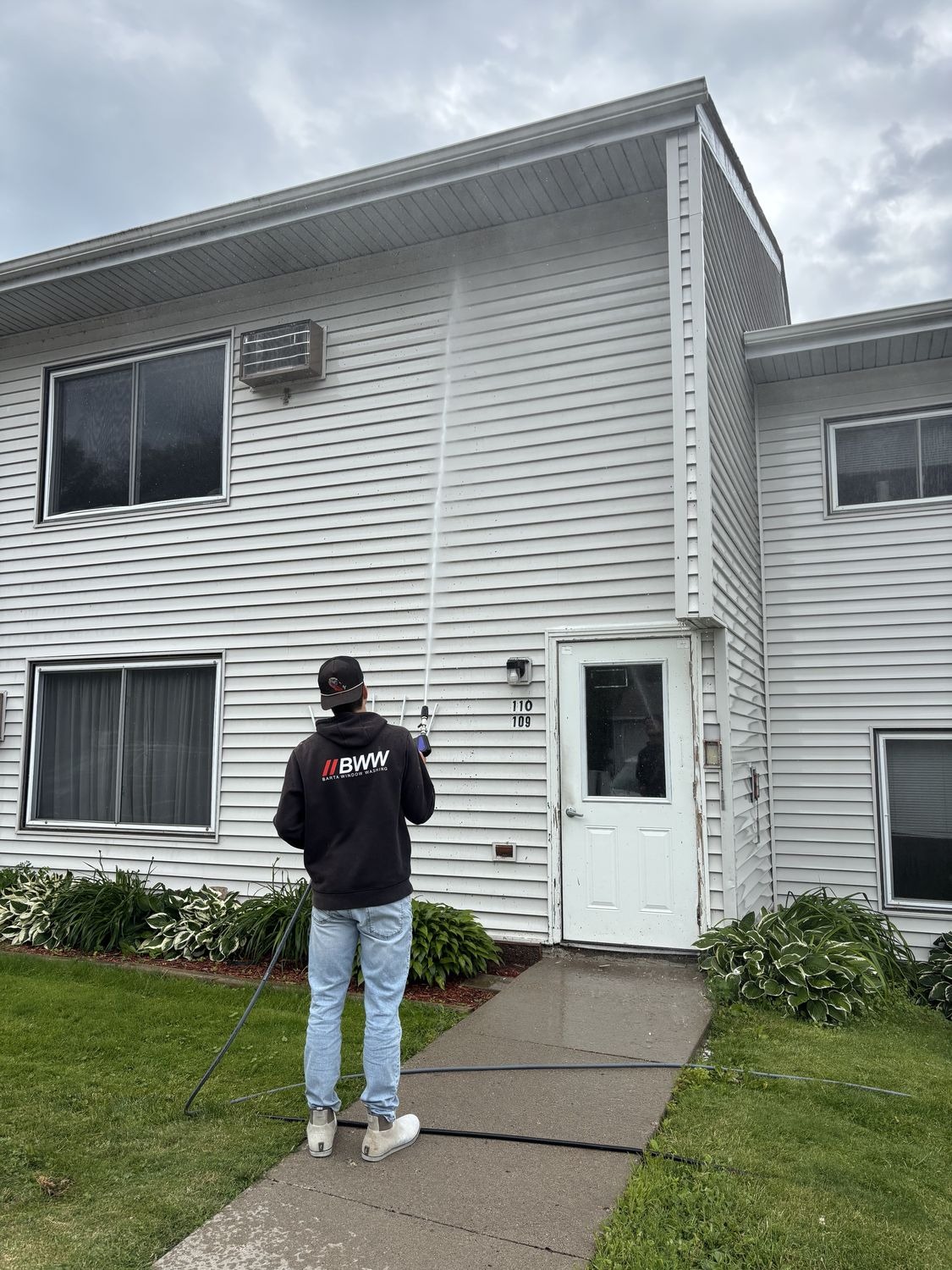 Soft washing a home's exterior siding with low-pressure equipment